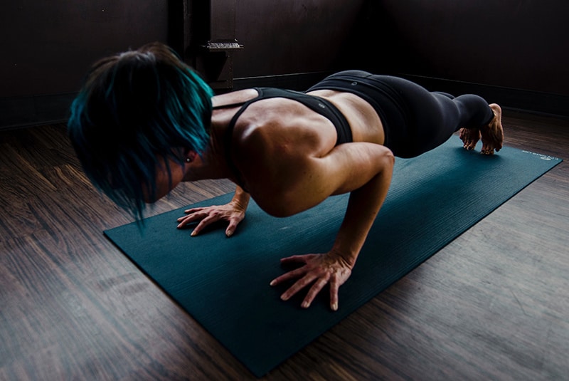 woman doing push-ups on blue mat