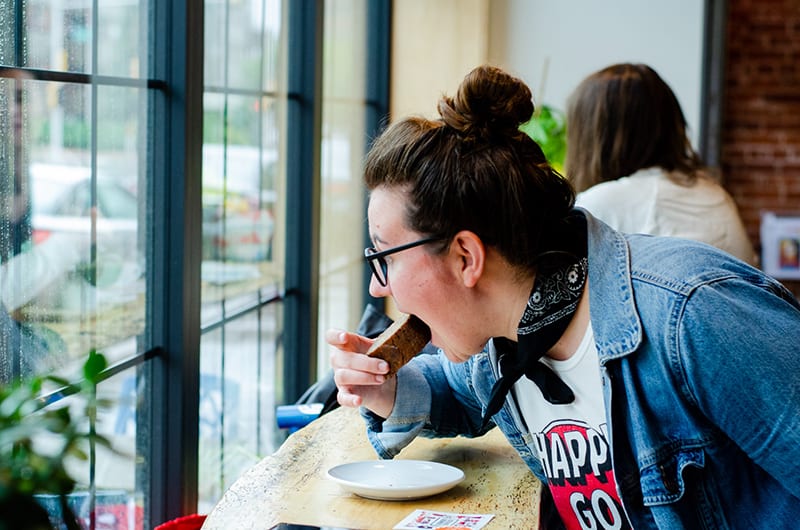 woman eating cake in front of the window