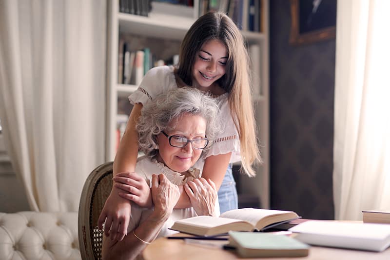 mulher abraça a sua avó enquanto lê um livro