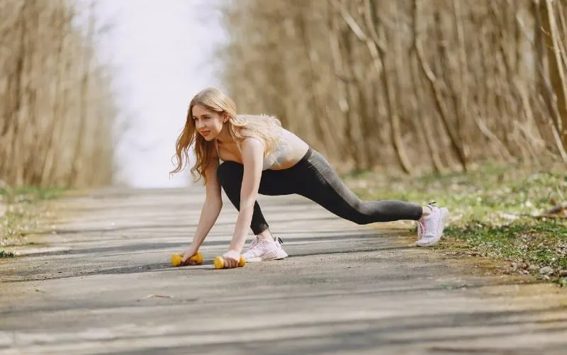 Happy woman exercising with dumbbells on a pavement