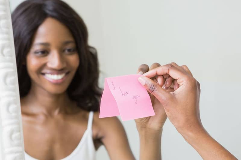 donna di fronte allo specchio che sceglie un biglietto d'amore su carta rosa
