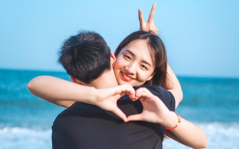 Woman holding man near the sea