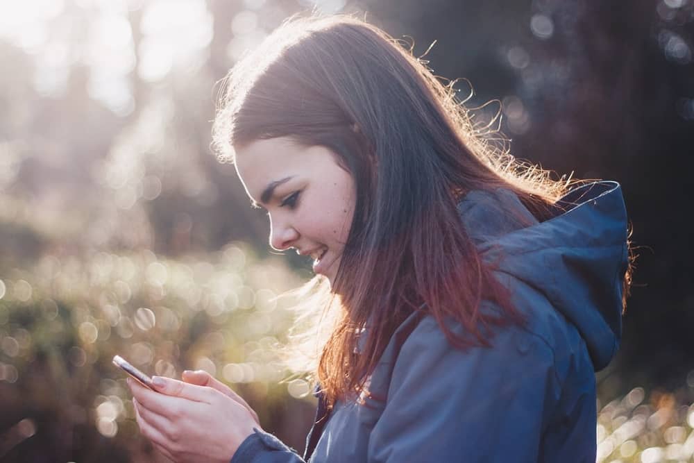 mujer con un teléfono en la mano sonriendo