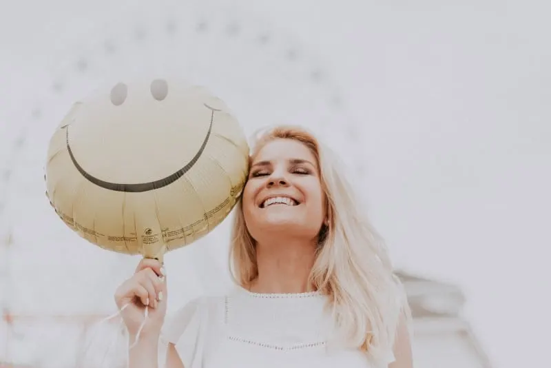 smiling woman holding smiley balloon