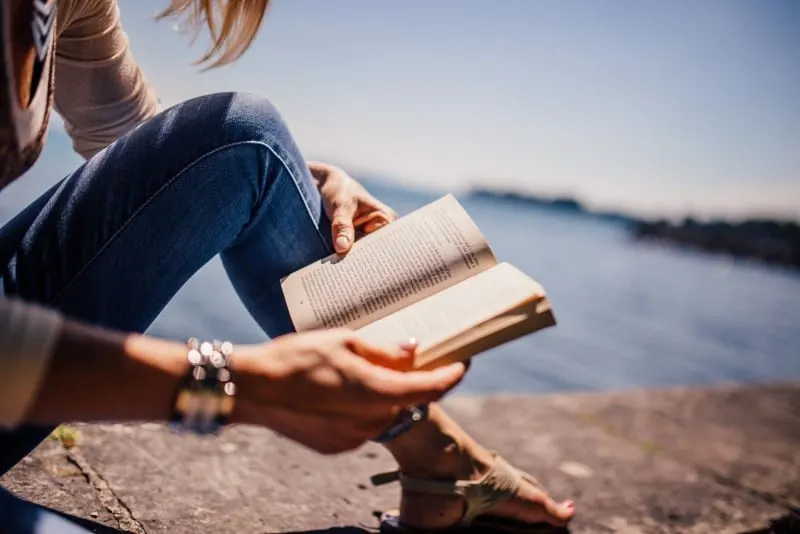 woman in blue denim jeans holding book