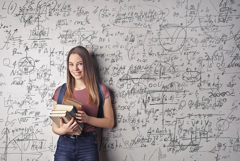 woman holding books in front of white board