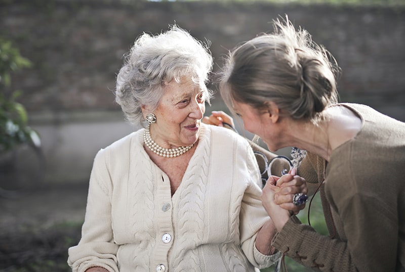 woman holding elder woman`s hand while they talking 