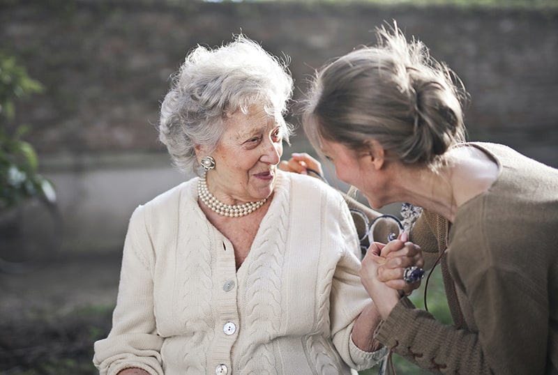 mujer cogiendo la mano de una anciana mientras hablan 