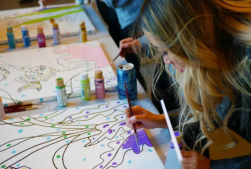 woman holding paintbrush while coloring a drawing