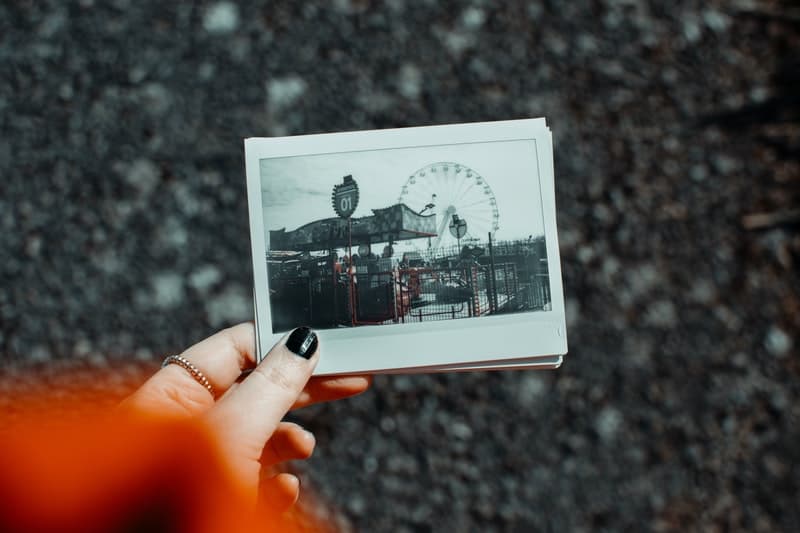 mulher com uma fotografia polaroid de um parque de diversões