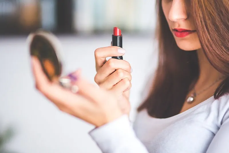 woman holding red lipstick and the mirror