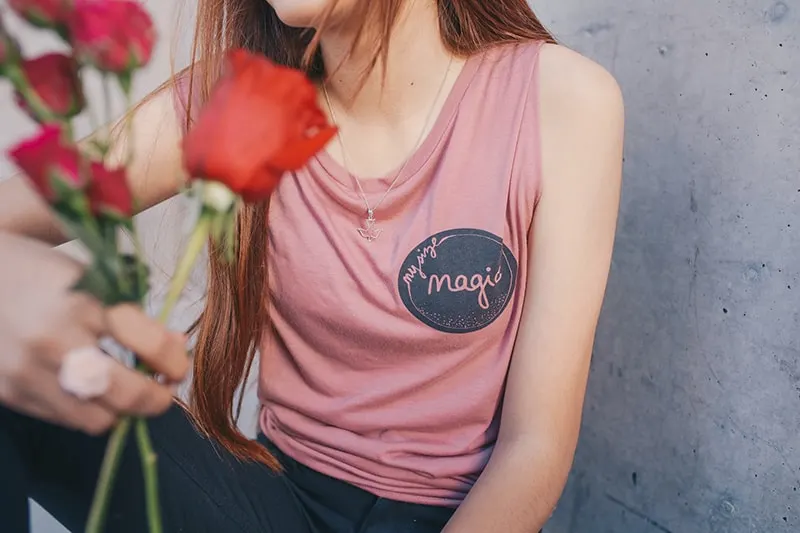 woman holding red roses near a grey concrete wall
