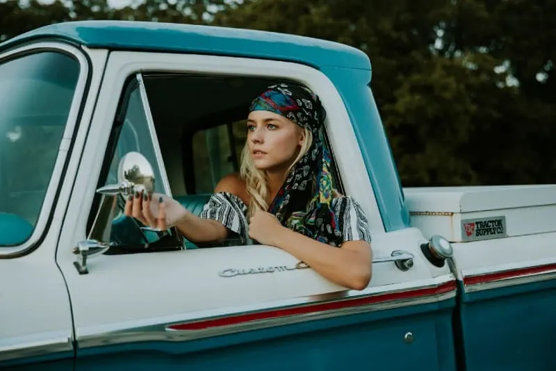 woman holding side mirror in white and green truck