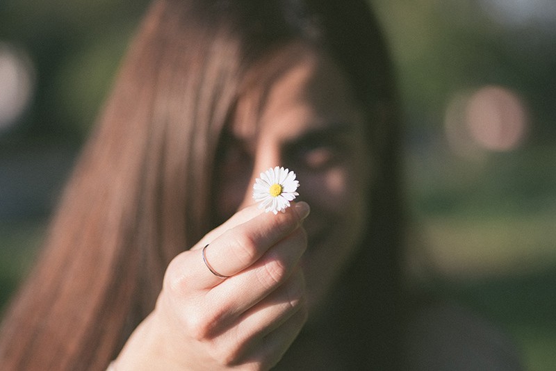 woman holding white flower and showing it