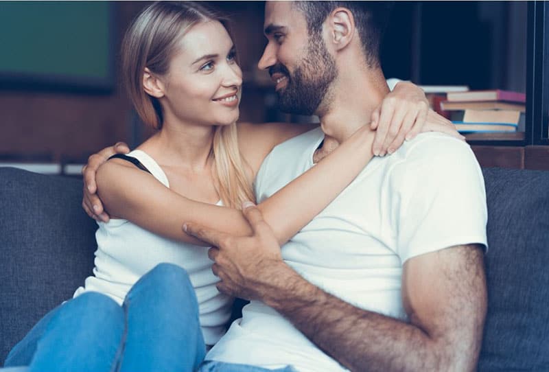 la mujer abraza al hombre con barba sentado 