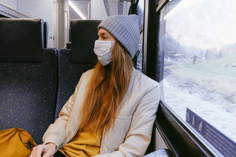 woman in a puv wearing mask and coat and a bonnet