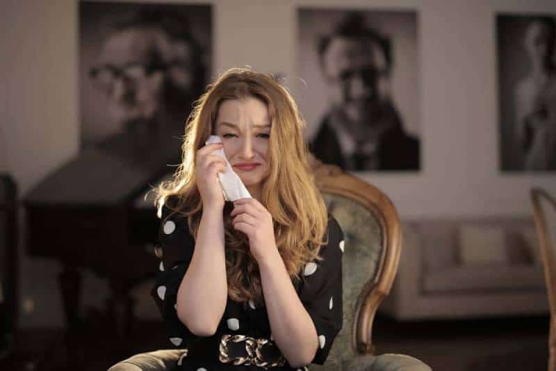 woman in black and white polka crying at home