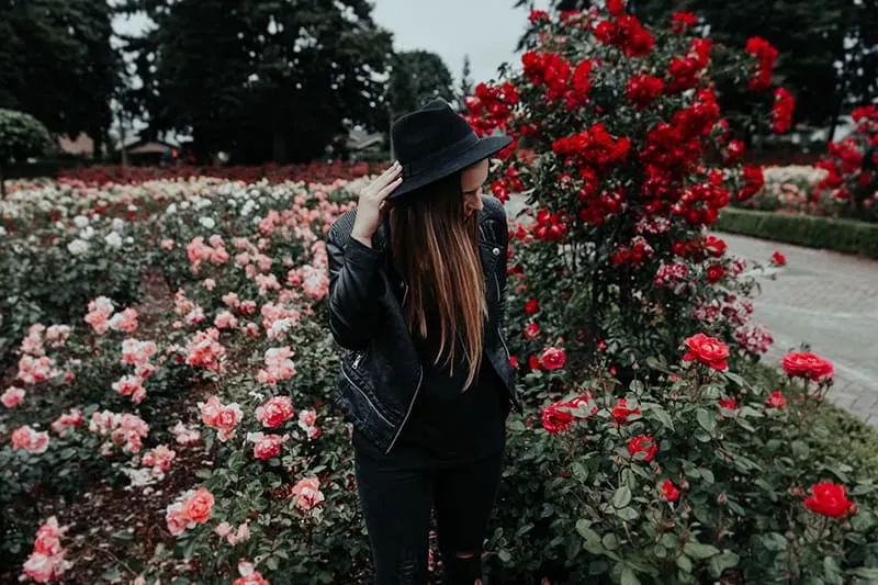 woman in black jacket standing near field of roses