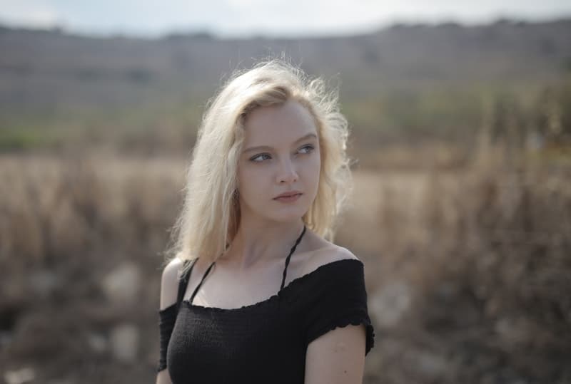 woman in black top with blonde hair near the field