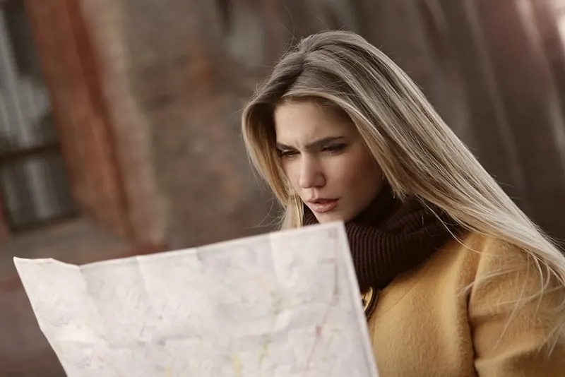 woman in brown coat holding a map