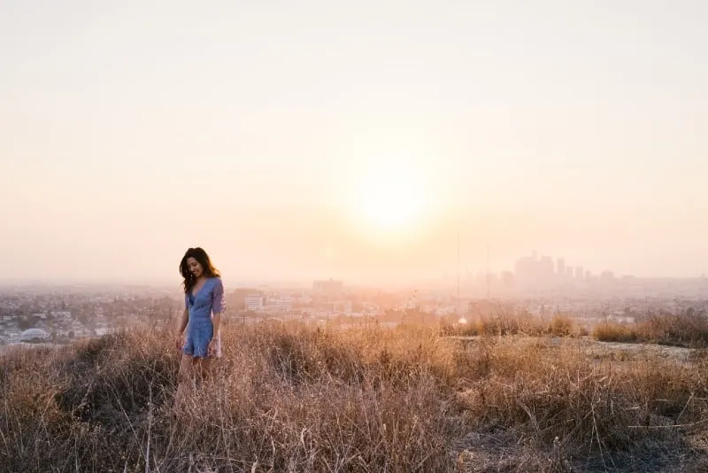 woman in blue dress standing in field during golden hour