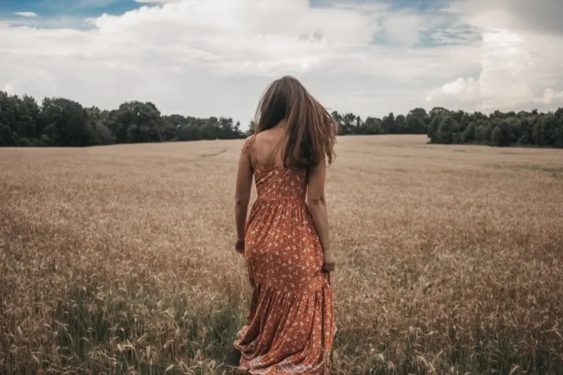 woman in orange dress standing on wheat field