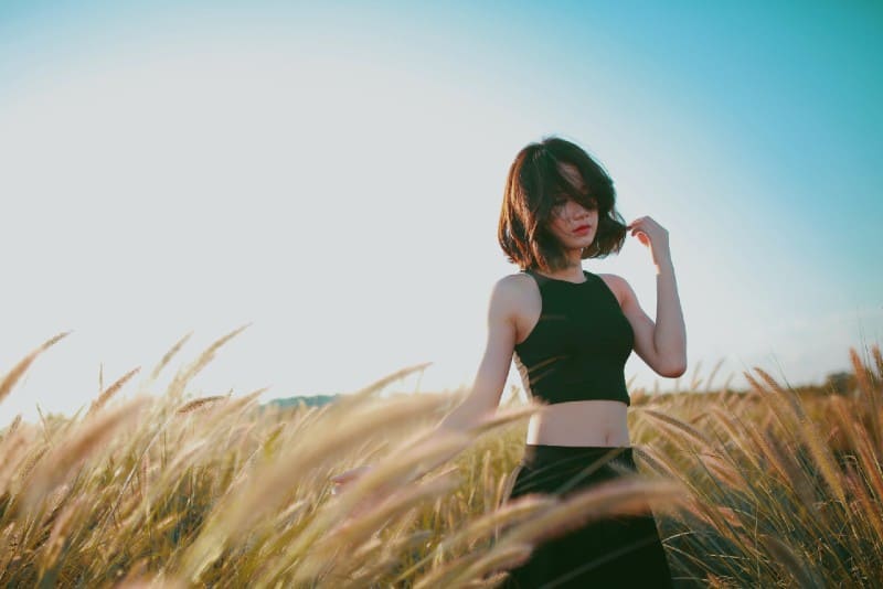 donna in top nero in piedi su un campo di grano