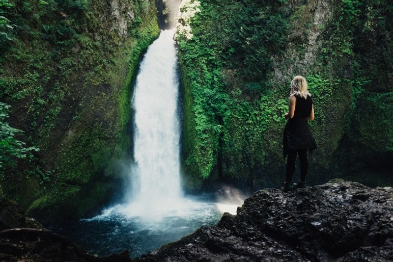 blonde woman in black top standing near waterfalls