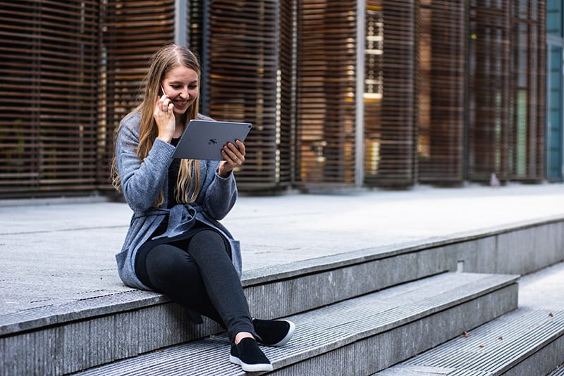 donna con cardigan grigio che parla al telefono tenendo in mano un iPad