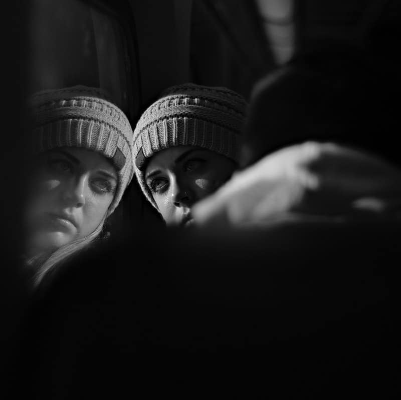 women in grayscale leaning on glass with a bonnet