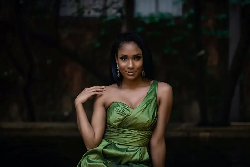 woman in green elegant dress touching shoulder with hand