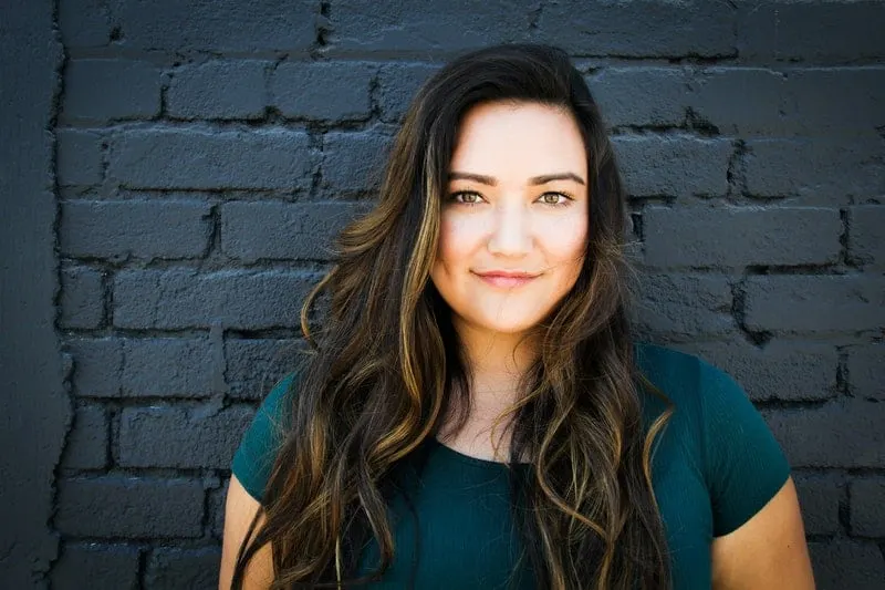 woman in green tshirt near a green brick wall