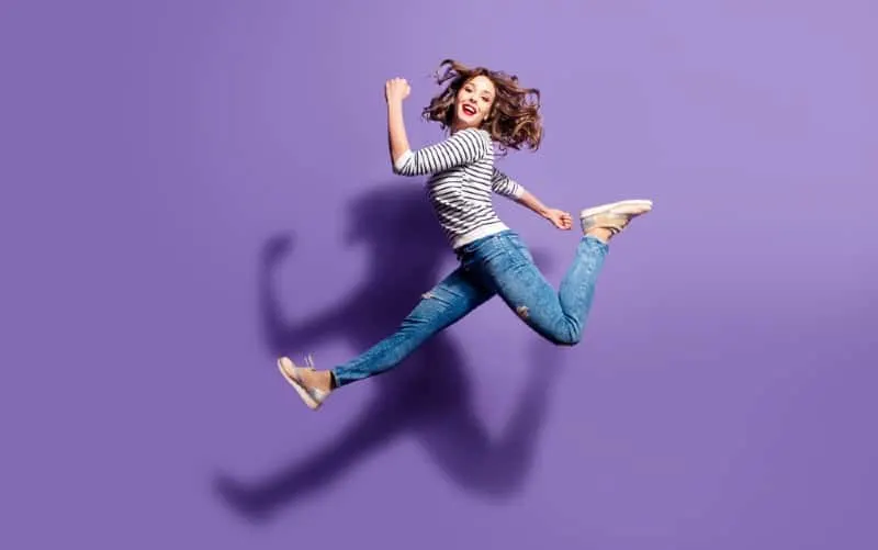 Happy woman in motion jumping on violet background