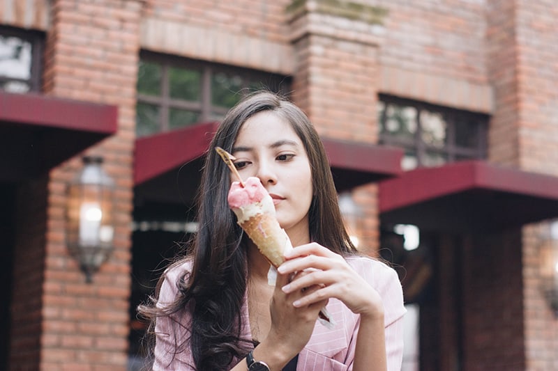 donna con blazer rosa che tiene in mano un gelato