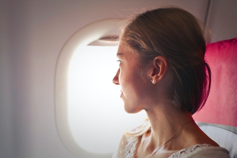 woman sitting on chair looking outside window on plane