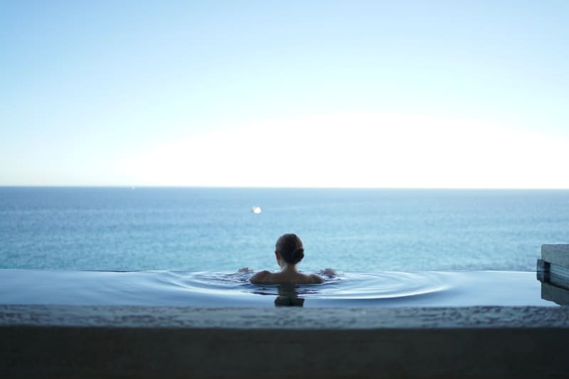 Donna che si rilassa in piscina guardando il mare