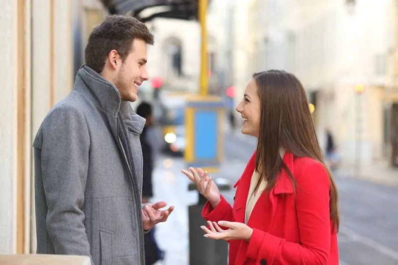 woman in red coat talking to man