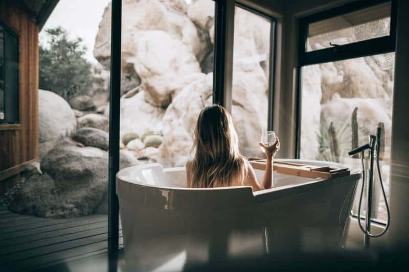 mujer en bañera blanca sosteniendo vaso transparente