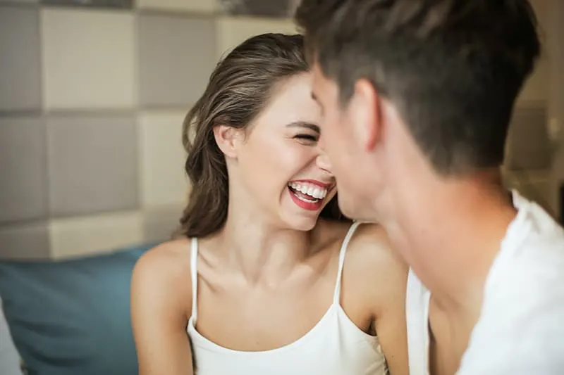 woman in white top laughing next to man