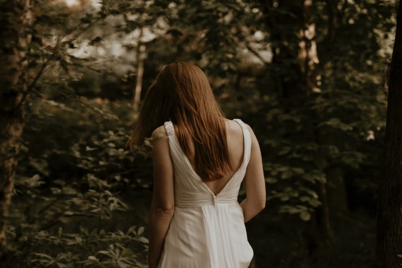 woman in white dress walking in the woods