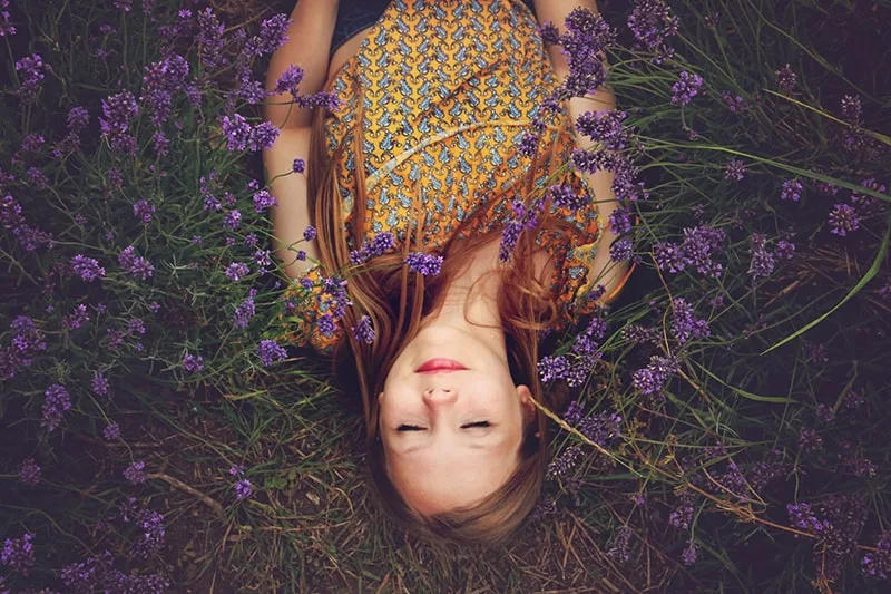 woman in yellow top sleeping beside lavenders