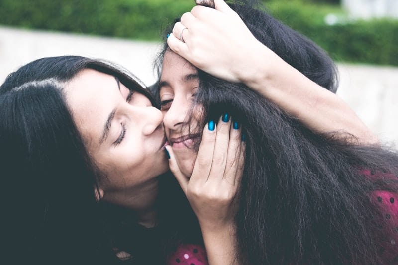 woman kissing cheek of girl wearing white and red polka dot