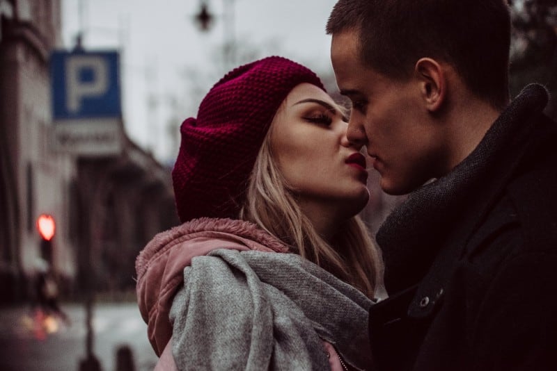 woman with red lipstick kissing man near sign