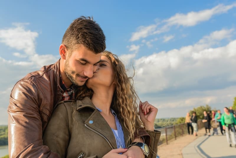 woman kissing man both in leather jackets