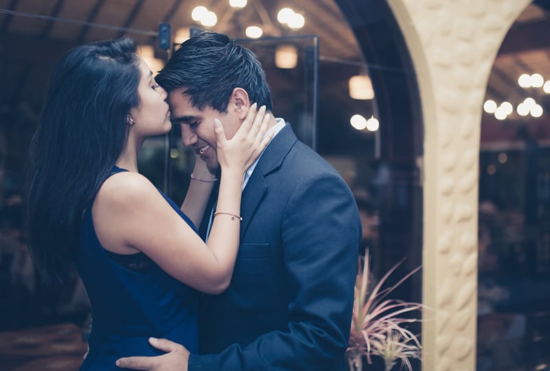 woman kissing man's forehead while standing outside