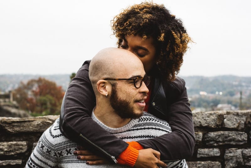 woman in black jacket kissing man's head