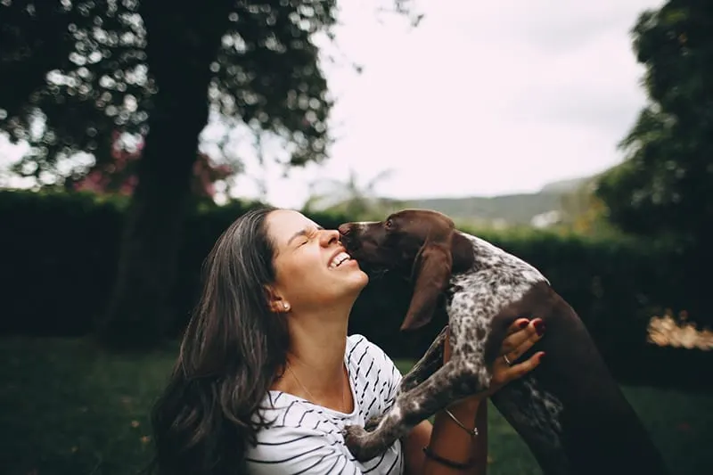 woman kissing the dog outdoors
