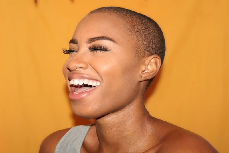 woman standing near yellow wall and laughing