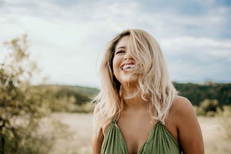 blonde woman in green top laughing outdoor