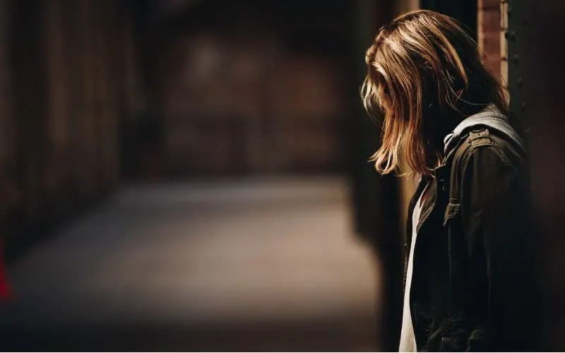 Woman leaning against wall facing down